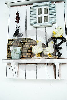 The wooden fence is decorated with three ceramic ducklings, faucets, cans and small ceramic windows.