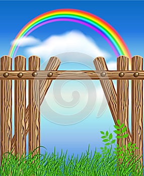 Wooden fence on green grass and rainbow