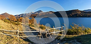 wooden fence and hiking trail on the banks of Campotosto Lake in the mountains of Abruzzo in Italy