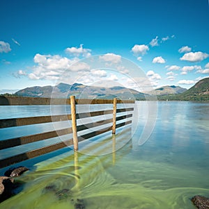 Wooden fence leads into Derwent water. Lake District.