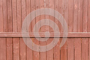 A wooden fence is painted with red paint as a background