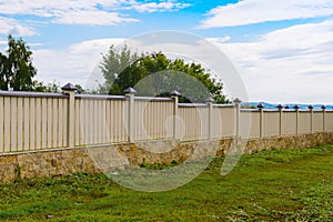 Wooden fence painted yellow with a stone base on the day