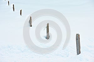 Wooden fence posts in deep snow winter guidance