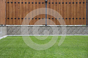 Wooden fence with stone basic and green grass in front.