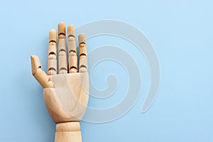 Wooden figure hand on blue background. Copy space