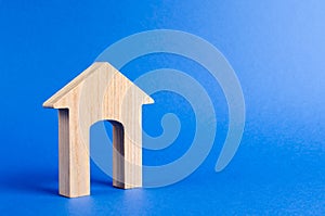 Wooden figure of a house with a large doorway on blue background. concept of buying and selling real estate, rent, investment.