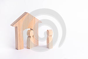 A wooden figure of a man meets a guest on a white background. Wooden house. The concept of an apartment house, real estate. Buying