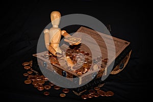 Wooden figure sitting in a wooden box with money