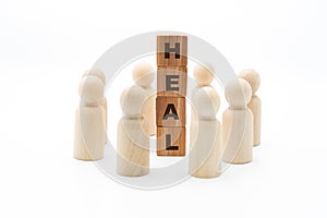 Wooden figures as business team in circle around word HEAL