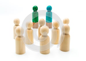 Wooden figures as a group listening to blue and green figures giving speech or debating