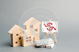 Wooden figures of houses and a poster with a symbol of falling value. concept of real estate value decrease. low liquidity