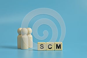 Wooden figures of people and alphabet letters with text SCM stands for Supply Chain Management