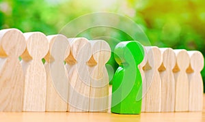 Wooden figures of people. The green man comes out with a team of workers. The concept of choosing a new leader. Choice of person.