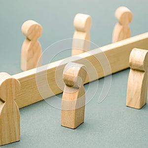Wooden figures of people are separated by a barrier. Social classes. Competition between teams. The concept of misunderstanding. A