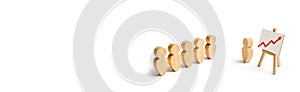 Wooden figures of people stand in the formation and listen to their leader. Business training, briefing and inspirational speech.