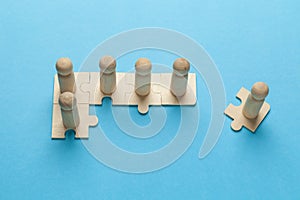 Wooden figures on puzzles on blue background as a symbol of team building. Organization group people in business. Cooperation and