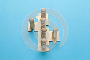 Wooden figures on puzzles on blue background as a symbol of team building. Organization group people in business. Cooperation and