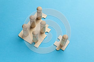 Wooden figures on puzzles on blue background as a symbol of team building. Organization group people in business. Cooperation and