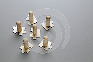 Wooden figures on puzzles on grey background as a symbol of team building. Organization group people in business. Cooperation and