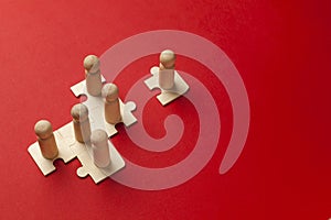 Wooden figures on puzzles on red background as a symbol of team building. Organization group people in business. Cooperation and