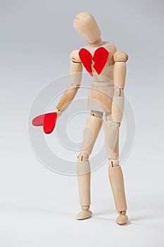 Wooden figurine with a broken heart and holding a red heart