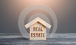 Wooden figurine of a house with word Real Estate. Buying and selling. Housing, realtor services. Construction industry, building