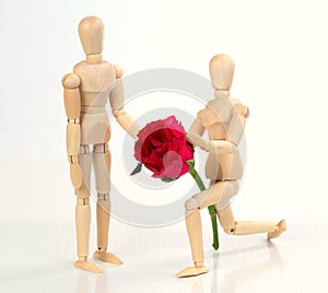 Wooden figurine man holding and giving rose