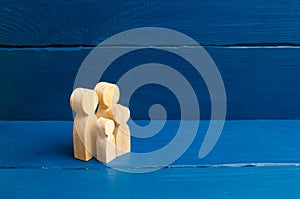 Wooden figurines of people in the shape of a family on a blue background. The concept of family values, family continuation