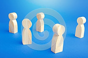 Wooden figurines of people stand on a blue background. Loneliness and disconnection. Safe spacing between persons, new normal. photo