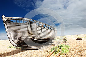Wooden fishing boat left to rot and decay on the shingle beach at Dungeness, England, UK.