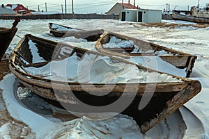 Wooden fishing boat on winter snow covered coast.