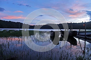 Wooden fishing boats in the lake. Blue sunrise sky colors over the lake in the early morning. Tranquil morning light view.