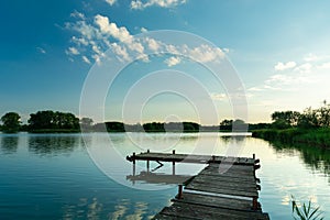 A wooden fishing pier and a calm blue lake