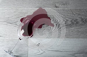 Wooden floor with overturned glass of red wine. Spilled wine on laminate floor with moisture protection