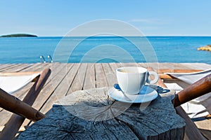 Wooden floor and sea view with chaise-longues and coffee