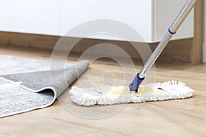 Wooden floor with white mop, cleaning service concept photo