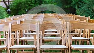 Wooden folding chairs in a garden before an outdoor wedding ceremony