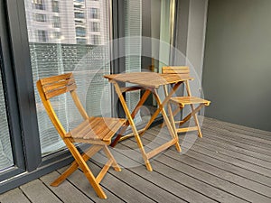 Wooden folding chairs and a table are located on the outdoor balcony. Home terrace. Patio furniture