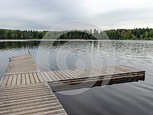 A wooden footbridge in the lake, empty beach in spring, last year`s reeds and the first greenery