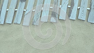 Wooden footbridge on a sandy beach. Uneven, damp wooden planks held together. The edge of the beach season at the hotel