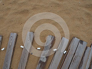 Wooden footbridge on a sandy beach. Uneven, damp wooden planks held together. The edge of the beach season at the hotel