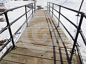 The wooden footbridge with snow all around.