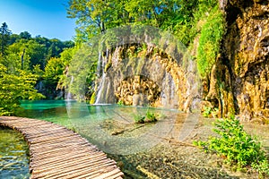 Wooden footpath at Plitvice national park, Croatia. Pathway in the forest near the lake and waterfall. Fresh beautiful nature,