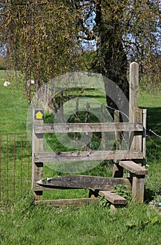 Wooden footpath stile and waymarker yellow arrow