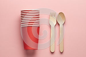 wooden forks and paper cup at pink coral background. eco-friendly and disposable kitchenware. flat lay. copy space