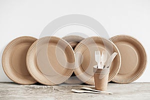 Wooden forks and paper cups with plates on wooden background. Eco friendly disposable tableware. Also used in fast food,