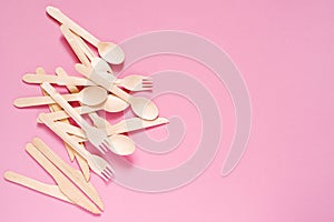 Wooden forks, spoons and knives on a pink surface, top view, copy space. Environment prote