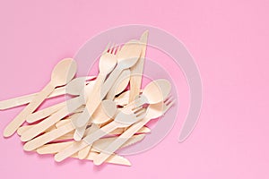 Wooden forks, spoons and knives on a pink surface, top view, copy space. Environment prote