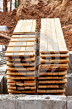 Wooden formwork boards stacked at the construction site. Storage of building materials at the construction site. Formwork for