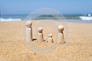 Wooden four figures of people on the sand of beach with sea view. Concept of happy family with two kids on holiday.